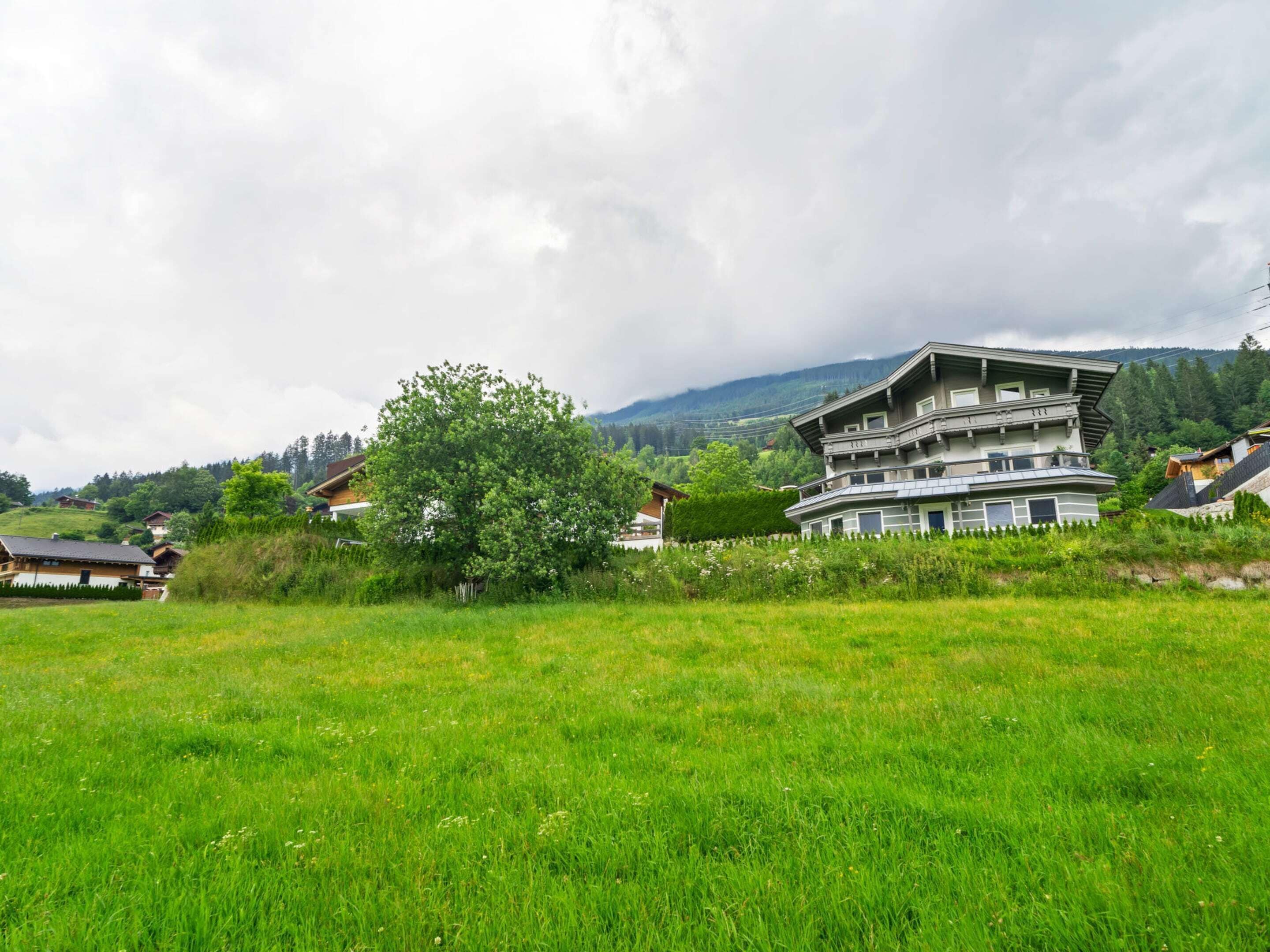 Ein großes, mehrgeschossiges Gebäude mit moderner Architektur, umgeben von üppigen grünen Feldern und einer bergigen Kulisse.