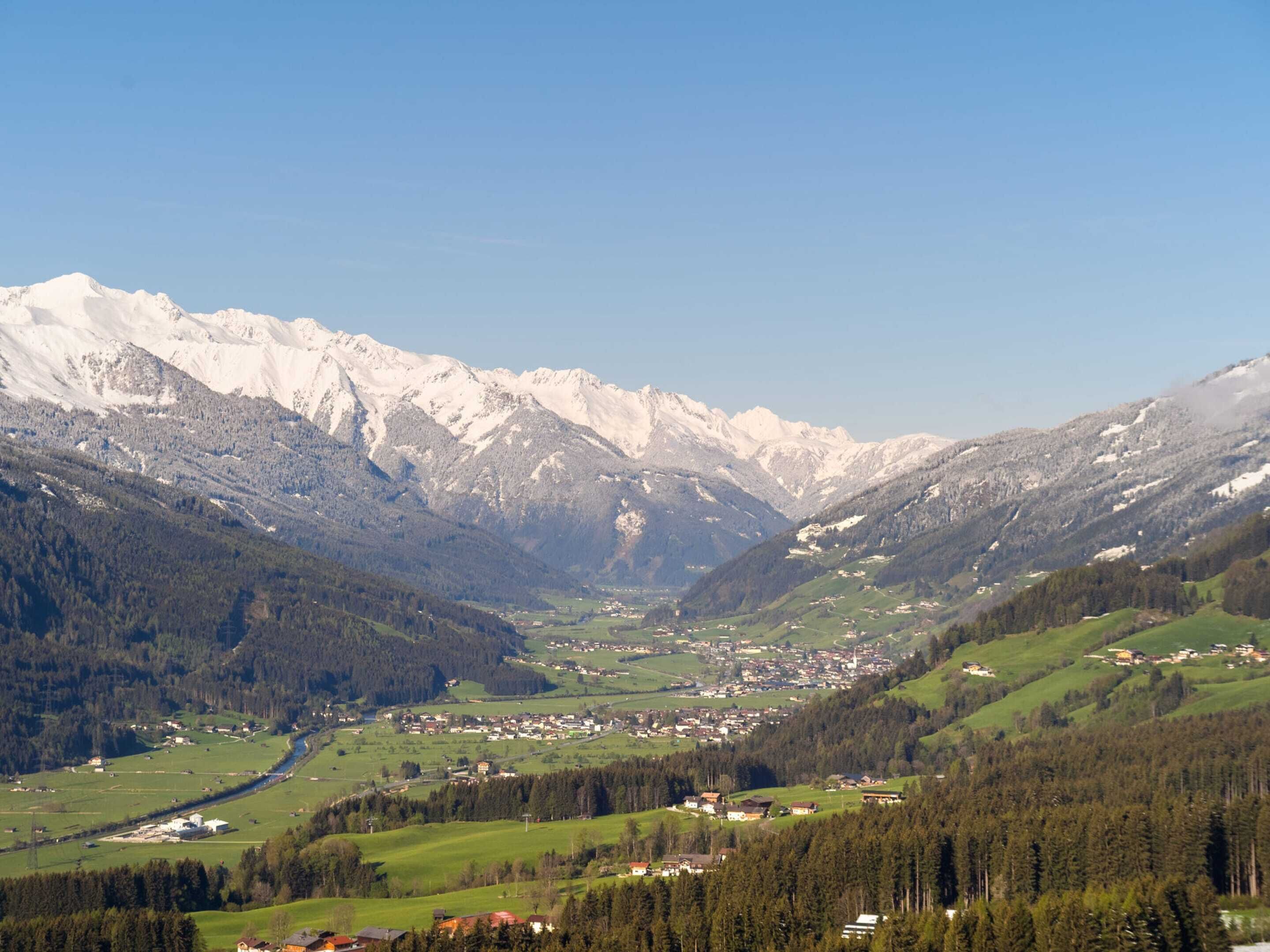 Un paysage montagneux avec une vallée, des maisons et une rivière.