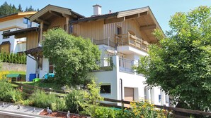 Ein mehrgeschossiges Gebäude mit Holzfassade, Balkonen und einem Gartenbereich mit verschiedenen Pflanzen und Blumen.