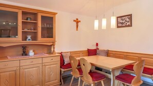 Un coin repas avec des meubles en bois, une croix accrochée au mur et un cadre photo.