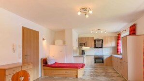 Une pièce de taille modeste comprenant un lit, un bureau, une chaise, un coin cuisine et une salle de bain.