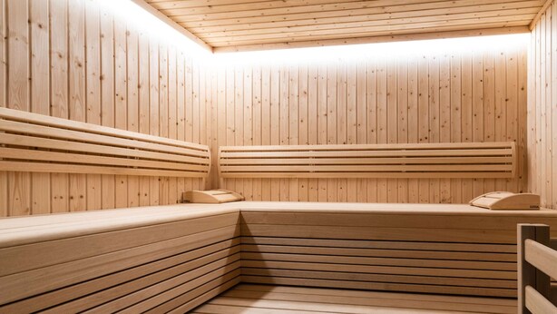 Un sauna avec des bancs en bois, un plafond en bois et un banc sur lequel est posée une serviette.