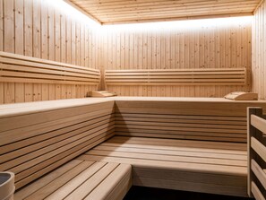 A sauna with wooden benches and benches, a wooden ceiling, and a bench with a towel on it. - Chalet in Zell am See Near Ski Slopes (Bruck an der Grossglocknerstrasse)