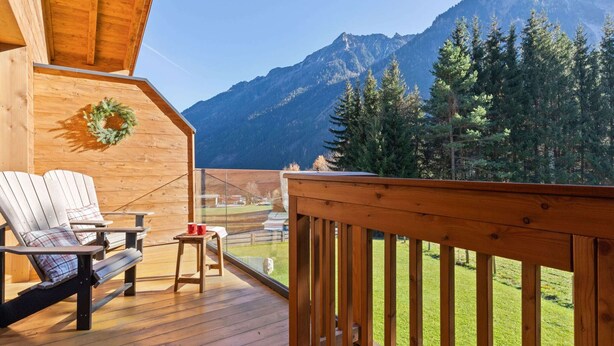 A wooden deck with two chairs and a small table, overlooking a mountainous landscape. - Chalet in Krimml Near Zillertal Ski Arena (Krimml)
