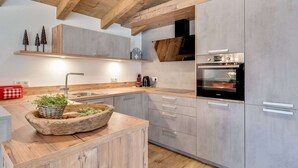 A modern kitchen with wooden beams, grey cabinets, and a built-in oven. - Chalet in Krimml Near Zillertal Ski Arena (Krimml)