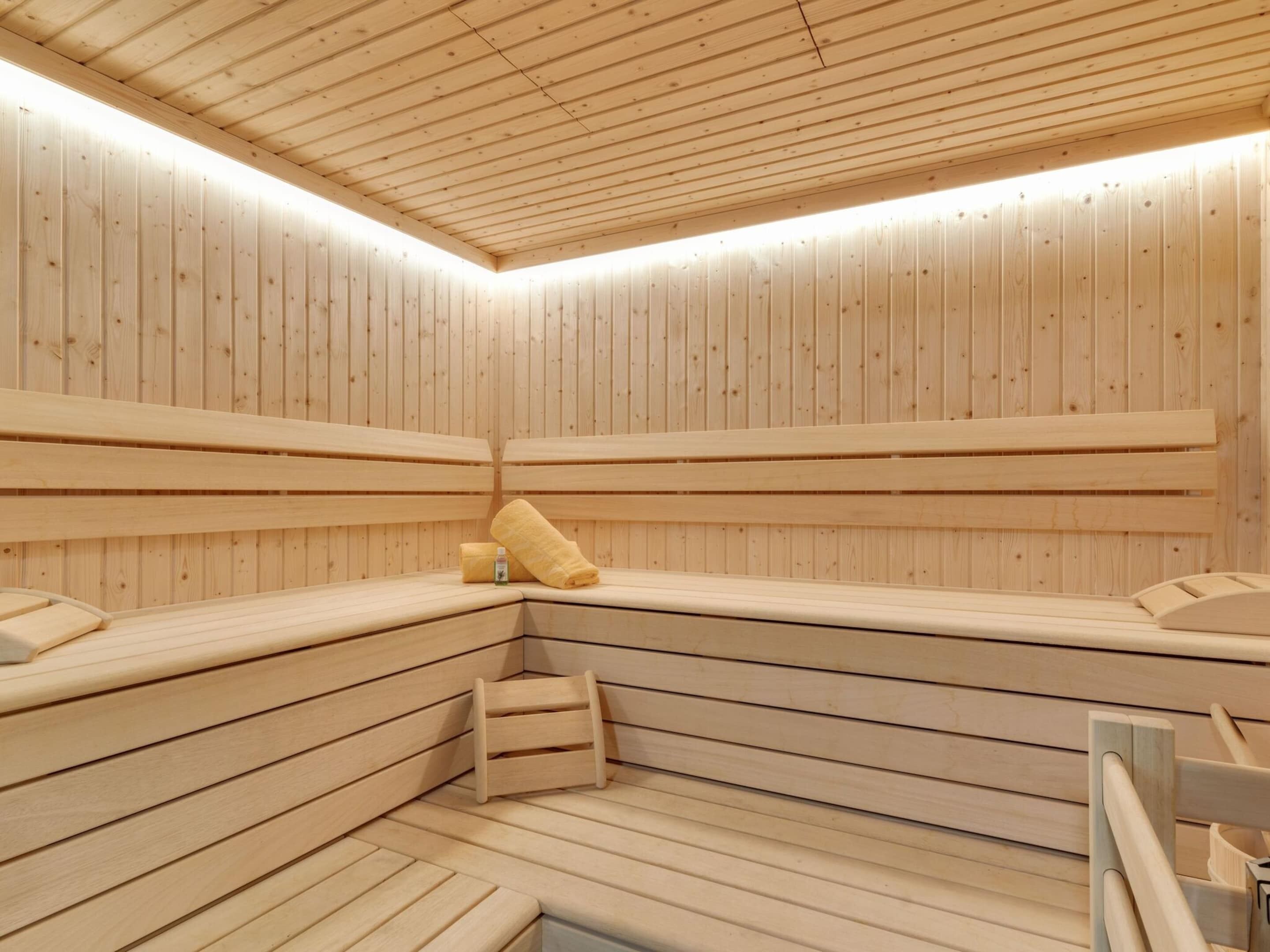 A sauna with wooden benches and benches, a towel, and a bottle.
