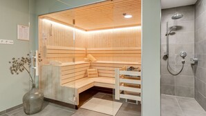 A modern sauna with wooden benches and glass walls, a shower area with grey tiles, and a vase with dried flowers on the floor. - Chalet in Krimml Near Zillertal Ski Arena (Krimml)