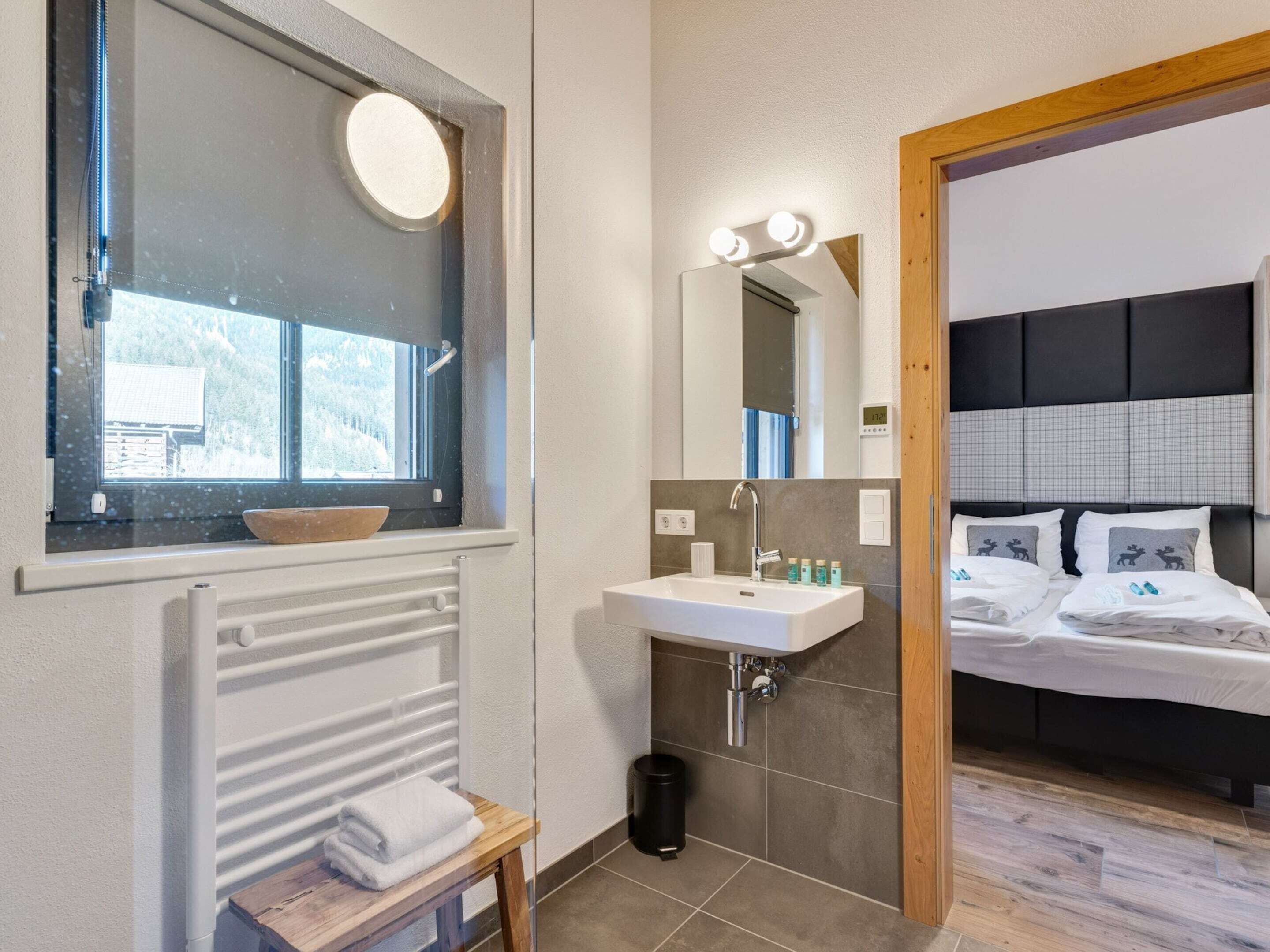 Een moderne badkamer met een wastafel, spiegel en raam.