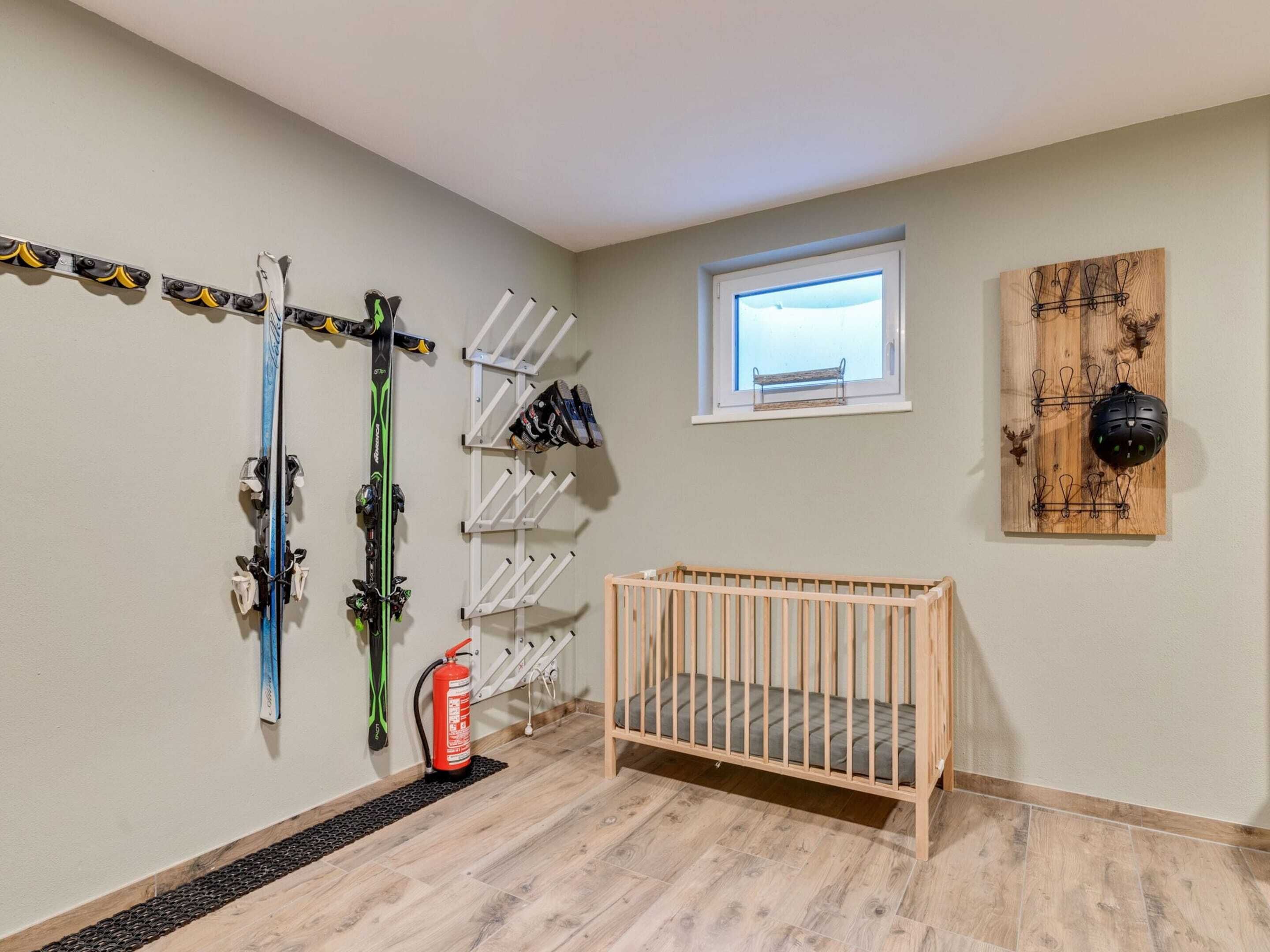A room with a crib, skis, and a fire extinguisher.