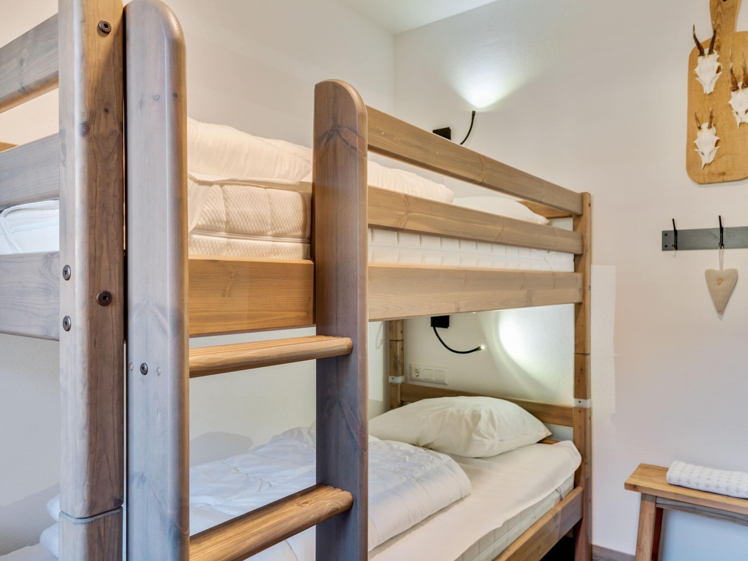 A bunk bed with wooden railings and a small bedside table with a lamp.
