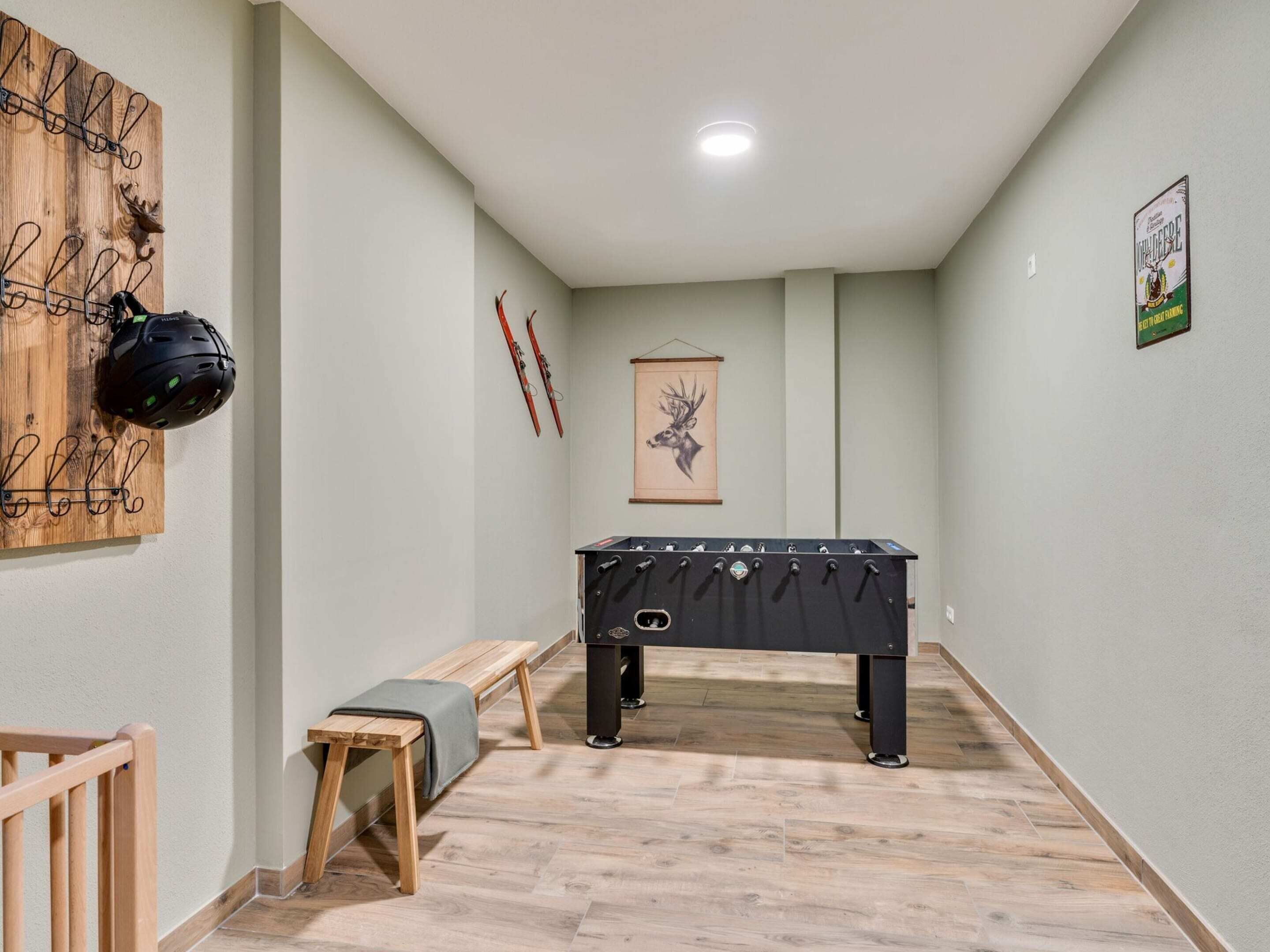 A narrow hallway with a pool table, a bench, and wall-mounted skis.