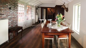 A dining area with a long wooden table, chairs, a bench, and a brick wall.