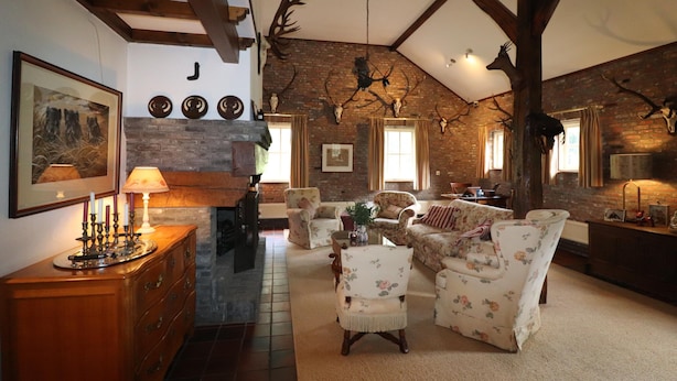 A rustic living room with exposed wooden beams, a fireplace, and antler decorations.