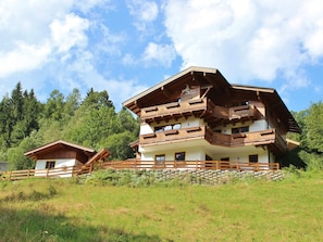 A multi-story chalet with wooden balconies, set in a mountainous area with lush greenery. - Comfortable Holiday Home (Viehhofen)