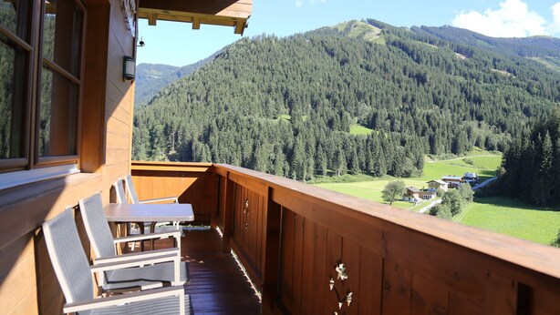 Ein Holzbalkon mit Blick auf einen bewaldeten Berg.