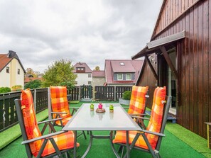An outdoor patio with a table and four chairs, surrounded by a wooden fence and a wooden building. - Cozy Apartment in Lichtenhain With Garden (Sebnitz)