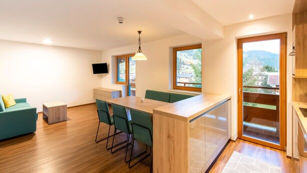 A modern kitchen with a wooden countertop, green chairs, and a built-in oven. - Apartment in Wald Near Zillertal Ski Area (Wald im Pinzgau)