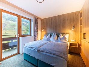 Ein Schlafzimmer mit Bett, Fenster, einer Holzwand und einer Tür.