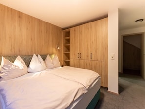 Ein Schlafzimmer mit Bett, Holzschrank und Teppichboden.