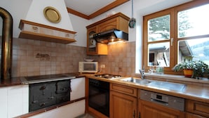 Une cuisine avec des meubles de rangement en bois, une cuisinière, un four à micro-ondes et un évier.
