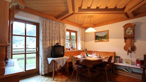 Un coin repas accueillant avec une table en bois, des chaises, un téléviseur et une horloge au mur.