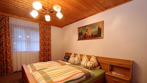 Une chambre à coucher avec un lit en bois, une table de chevet, un bureau et un tableau accroché au mur.