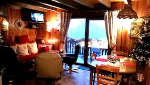 A cozy room with a television, a dining table with chairs, a Christmas tree, and a view through a window. - Spacious Chalet for 4 in Hommert (Hommert)