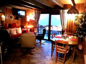 A cozy room with a television, a dining table with chairs, a Christmas tree, and a view through a window. - Spacious Chalet for 4 in Hommert (Hommert)