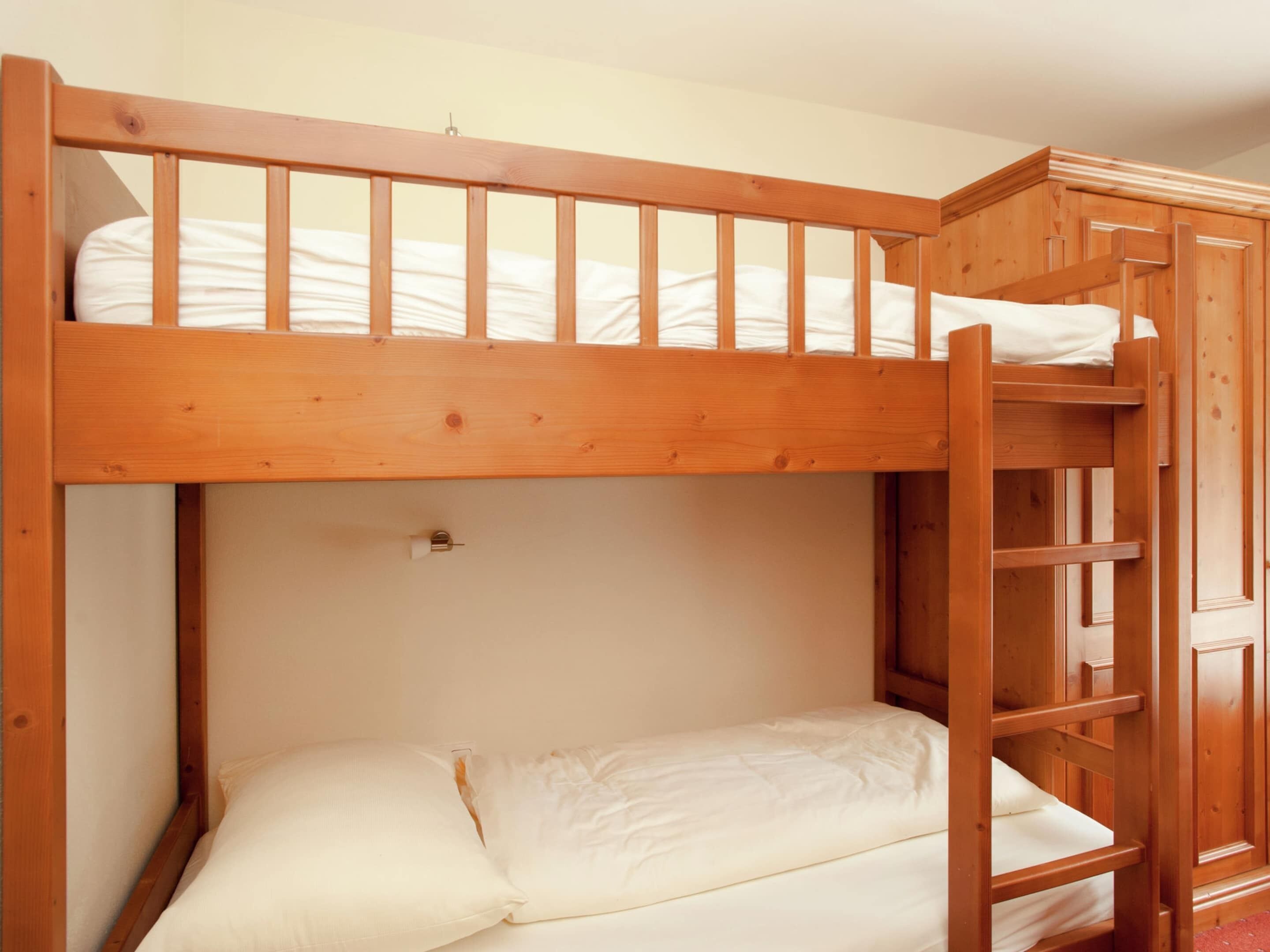 A bunk bed with a wooden frame and white bedding.