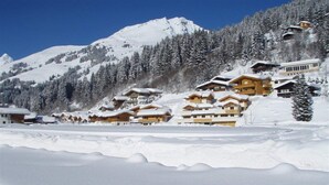 A snow-covered mountain with wooden chalets and a clear blue sky. - Chalet in Saalbach With Sauna (Saalbach-Hinterglemm)