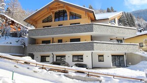 A multi-story building with a wooden facade and stone accents, featuring balconies and large windows. - Luxury Chalet with Sauna near Ski Area in Salzburg (Sankt Johann im Pongau)