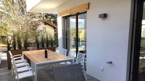 An outdoor patio with a wooden table and white chairs, a bottle of wine, and a glass. - Luxury Chalet with Sauna near Ski Area in Salzburg (Sankt Johann im Pongau)