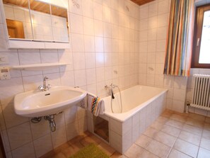 A bathroom with a sink, bathtub, and a window with curtains. - Spacious Apartment near Ski Area in Salzburg (Dienten am Hochkoenig)