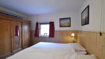 Un dormitorio con una cama grande, un armario de madera, una ventana con cortinas e imagen enmarcada en la pared.