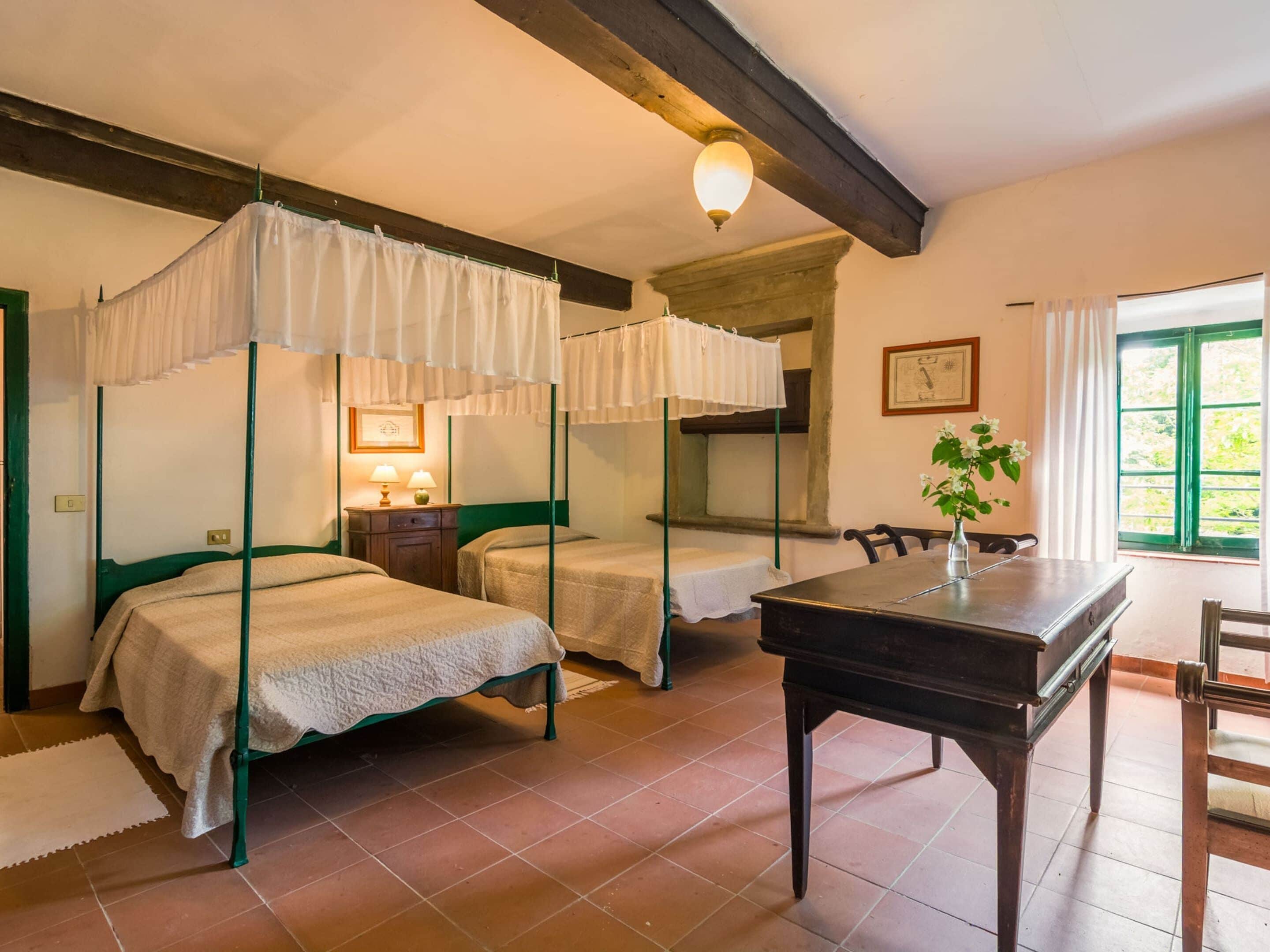 A room with two beds, a table, and a window.