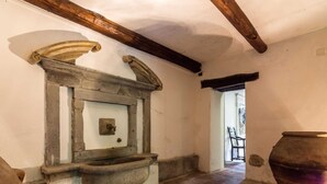 Un interior rústico con un lavabo de piedra, vigas de madera y una gran maceta de barro.