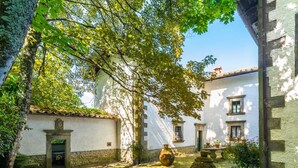 Un patio con edificios blancos, muros de piedra y plantas en macetas.