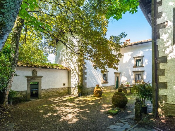 A courtyard with white buildings, stone walls, and potted plants. - Spacious Villa Retreat (San Marcello Piteglio)