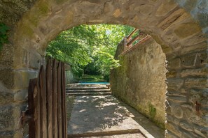 A stone archway leading to a pathway surrounded by greenery. - Spacious Villa Retreat (San Marcello Piteglio)