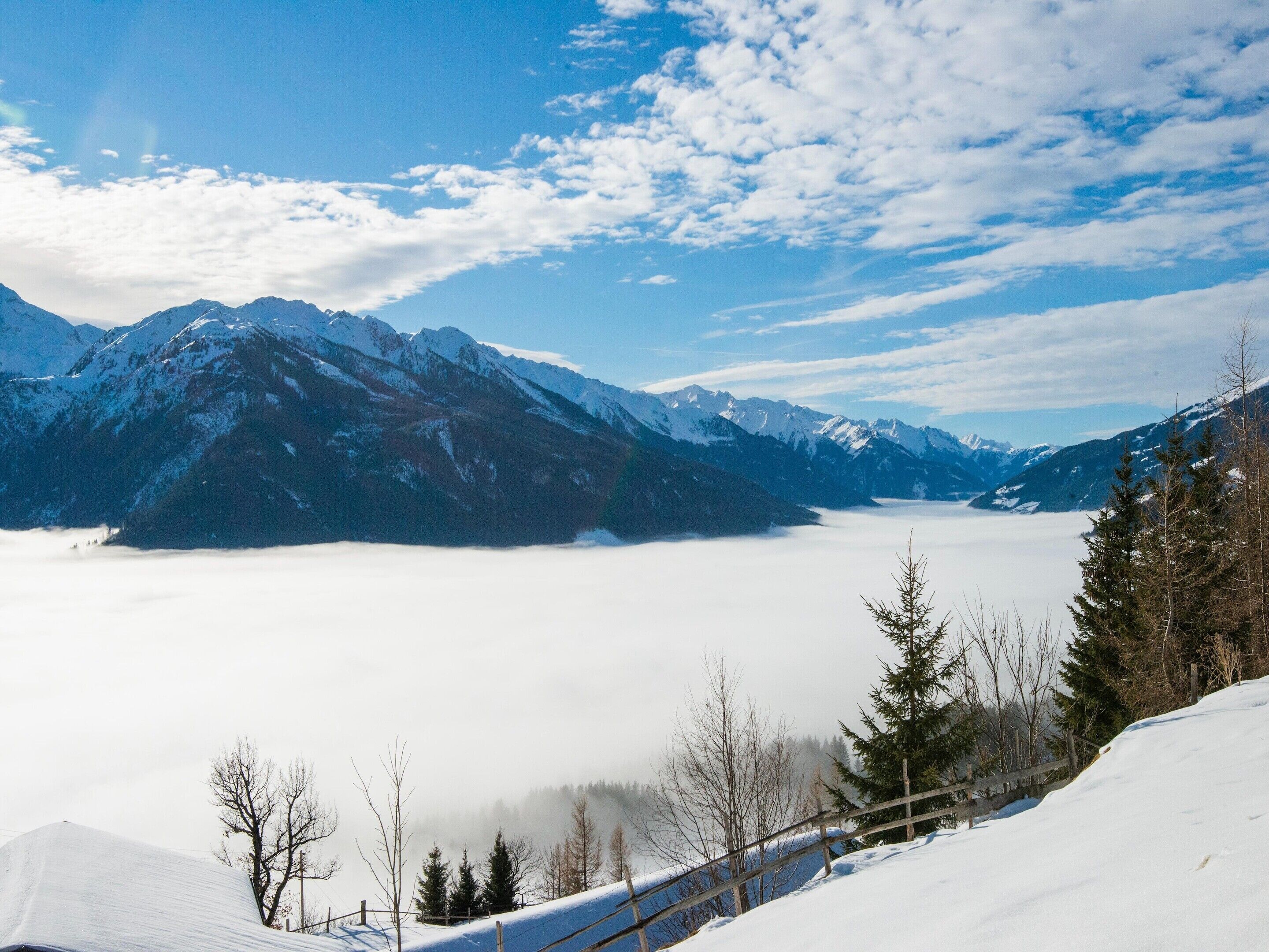 A snowy mountain landscape with a clear sky and a valley below.