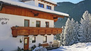 A traditional Alpine-style building with a wooden balcony, a snow-covered roof, and a mountainous backdrop. - Apartment in Zillertal Near Ski Slopes (Fuegenberg)