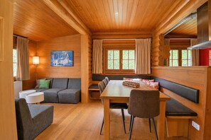 A log cabin interior with a dining table, benches, a sofa, and a painting on the wall. - Spacious Chalet in Wörgl-boden near Ski Area (Woergl)