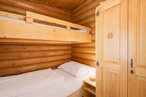 A wooden cabin room with a bunk bed, a wooden wardrobe, and a bedside table with a lamp. - Spacious Chalet in Wörgl-boden near Ski Area (Woergl)