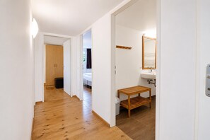 A hallway with wooden flooring, a wooden door, a white wall, a wooden bench, and a mirror above a sink. - Spacious Chalet in Wörgl-boden near Ski Area (Woergl)