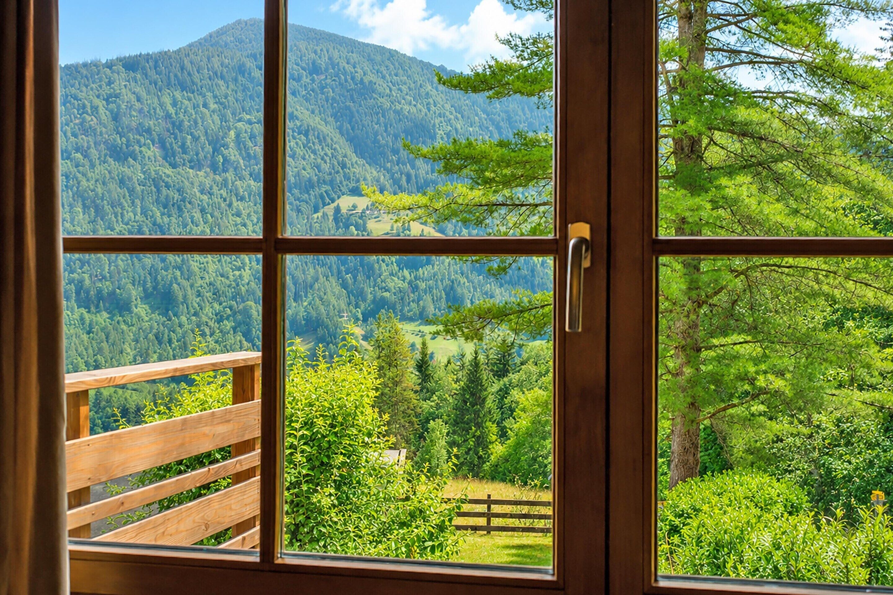 A wooden balcony with a view of a forested mountain.