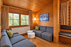 A cozy cabin interior with a sofa set, a painting, and a window with curtains.