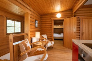 A log cabin interior with a bed, two chairs, a table, and a kitchen area. - Spacious Chalet in Wörgl-boden near Ski Area (Woergl)