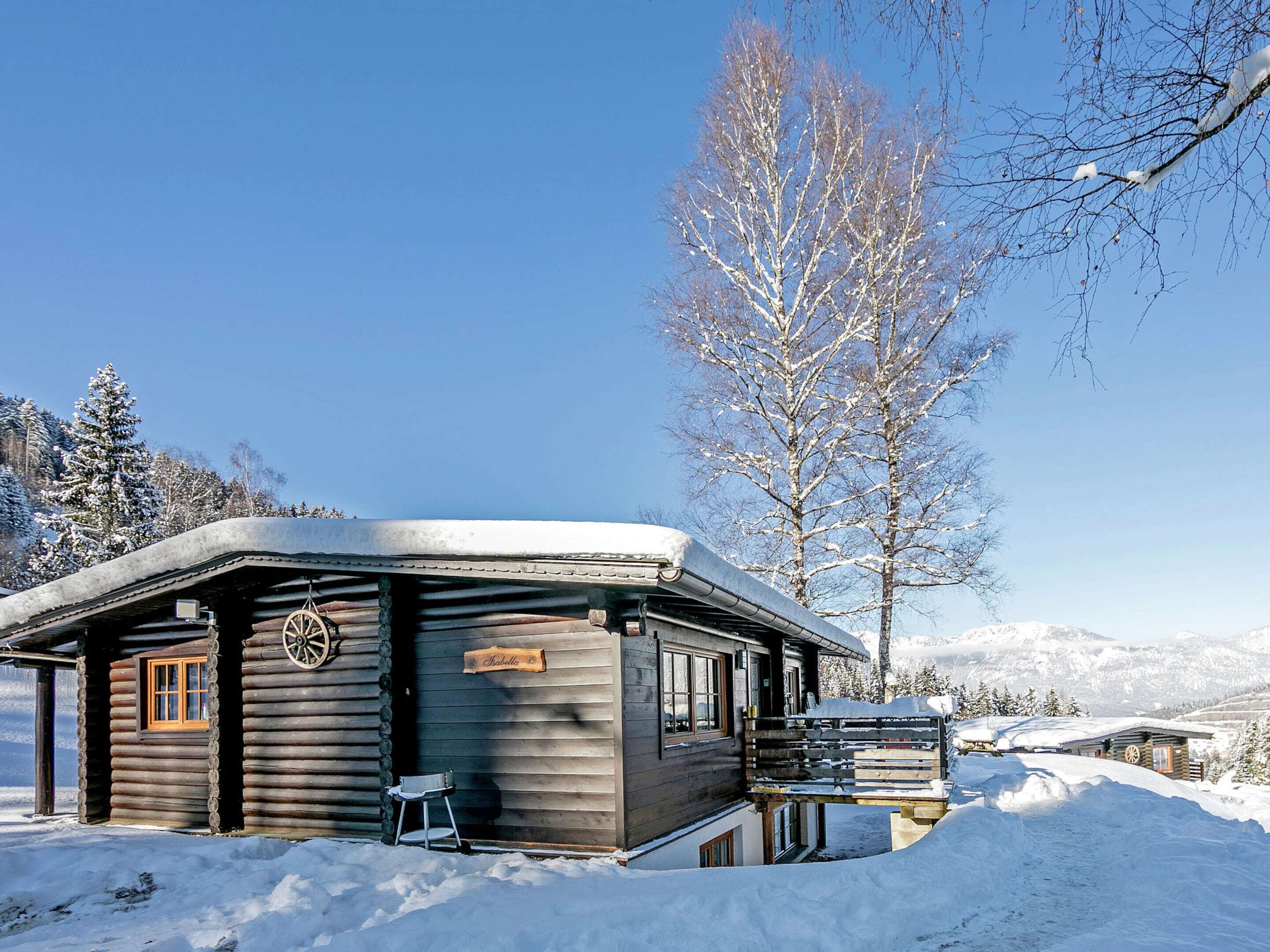 Une cabane en rondins de bois, avec une porte ornée d’une roue et une enseigne sur laquelle on peut lire « Stabholz ».