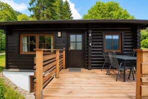 A log cabin with a wooden deck, a dining table with chairs, and a door with a number. - Spacious Chalet in Wörgl-boden near Ski Area (Woergl)