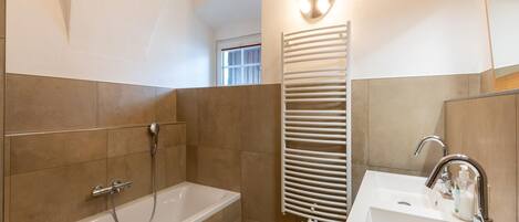 Une salle de bain moderne équipée d’une baignoire, d’une douche et d’un lavabo.